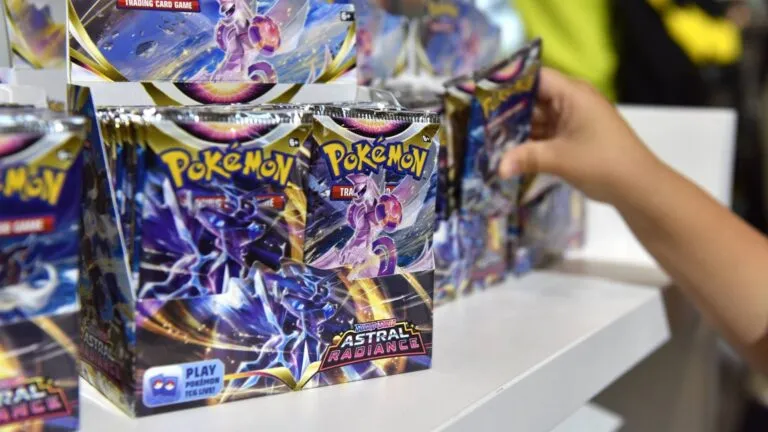 Bustine di carte del gioco di carte collezionabili Pokémon esposte su un tavolo mentre una mano seleziona un pacchetto.